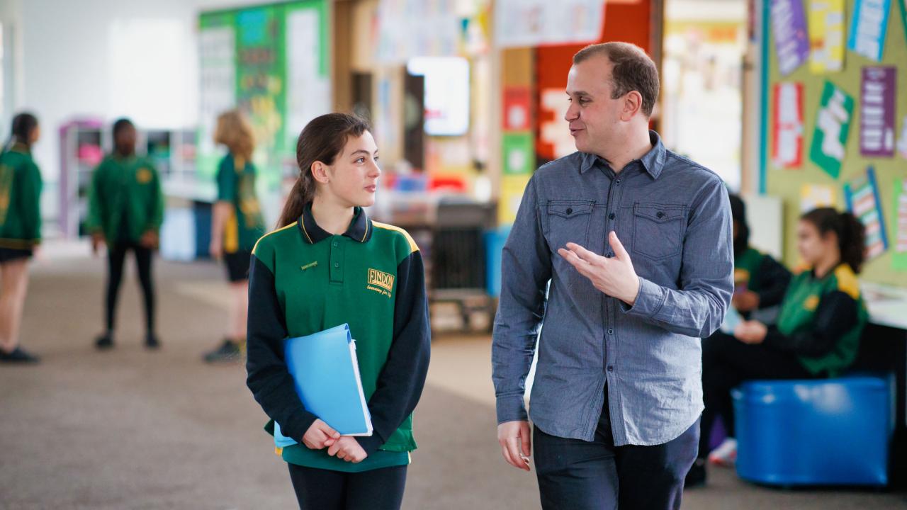 Male teacher walking with primary student