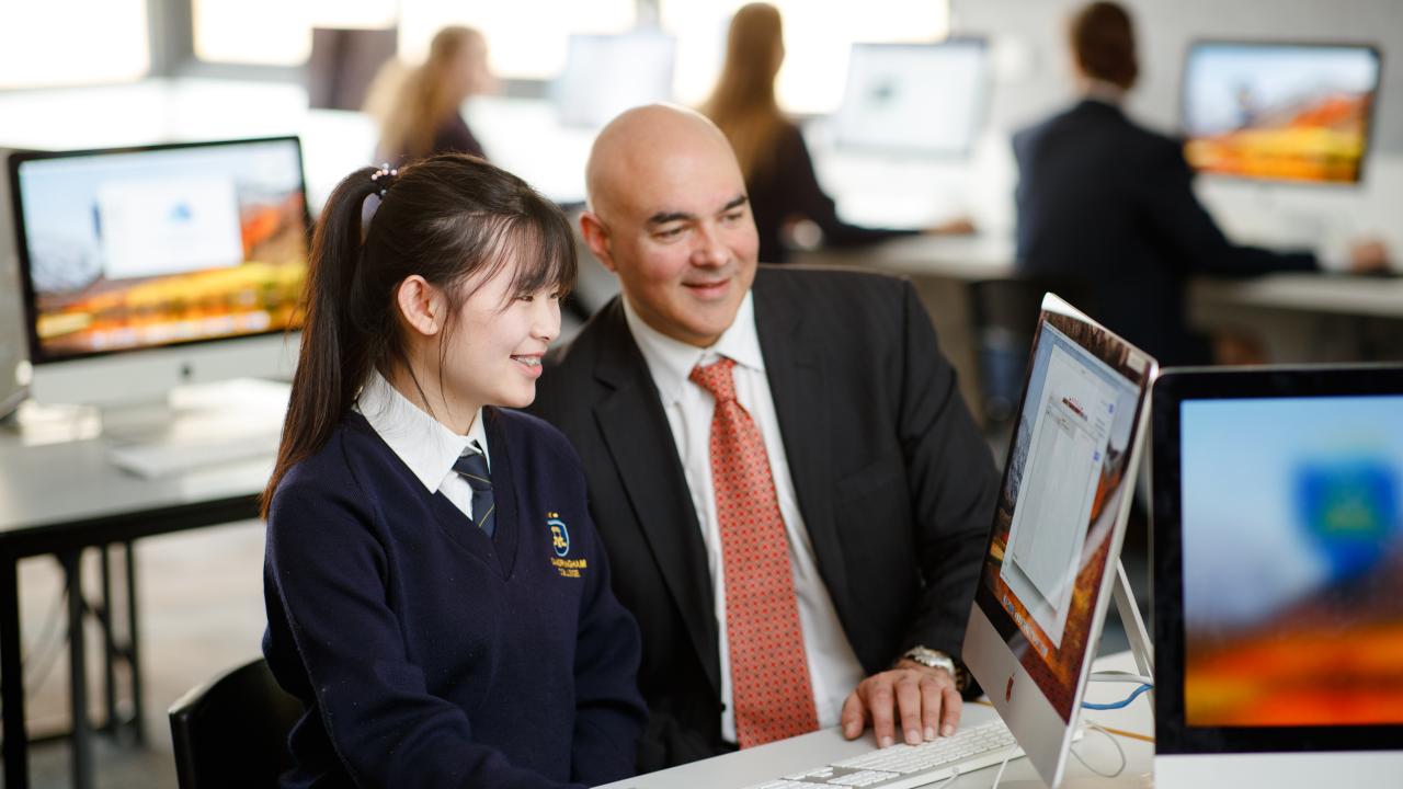 Male teacher with high school students at computer