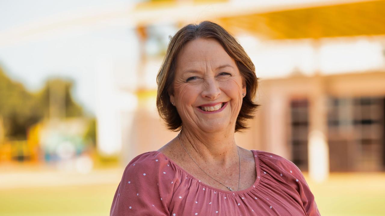 Woman looking directly into camera in front of a school building