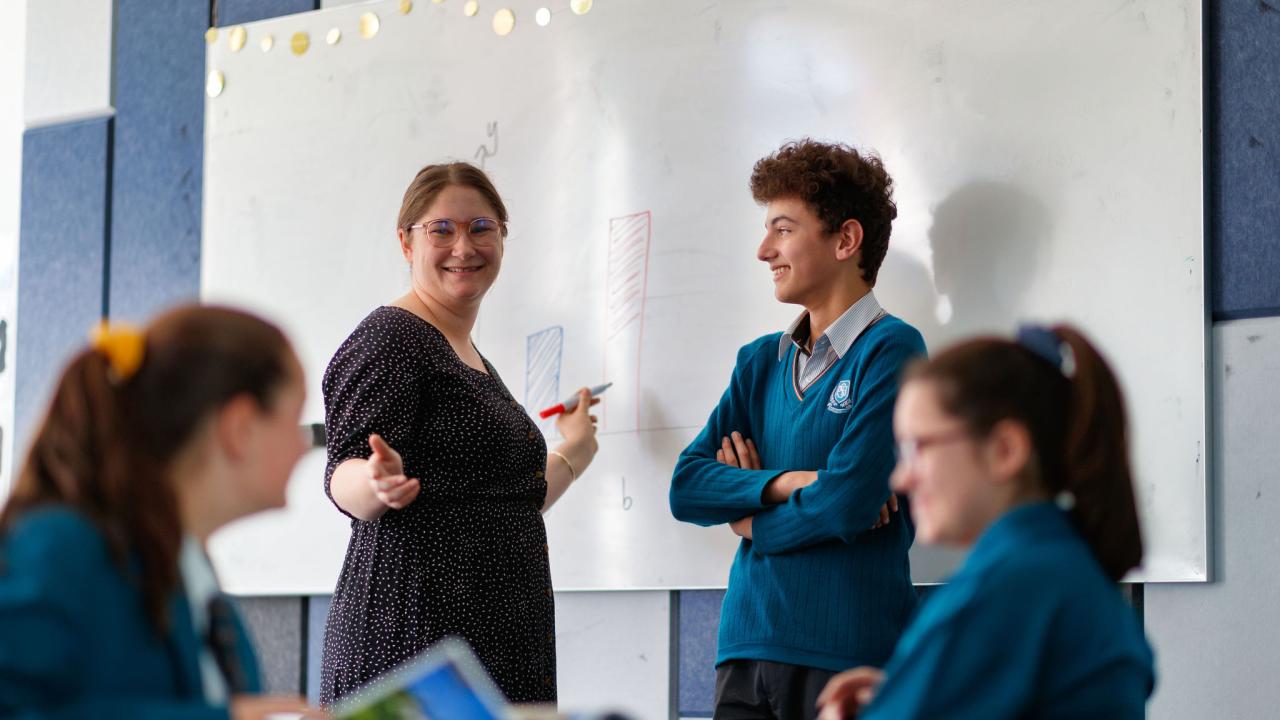 Teacher standing at whiteboard teaching. 