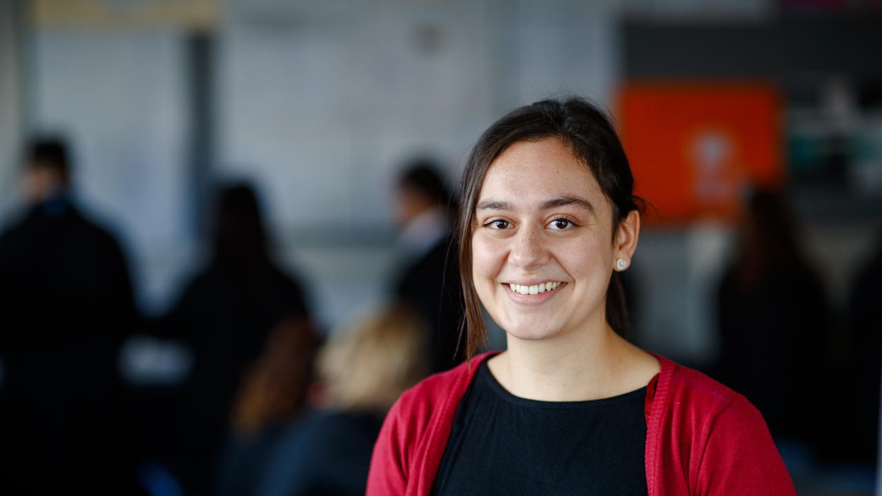 Teacher looking to camera with classroom in the back ground. 