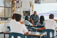 Teacher seated in front of class of seated students