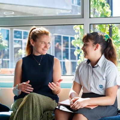 Teacher sitting between two students talking. 