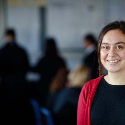 Teacher looking to camera with classroom in the back ground. 