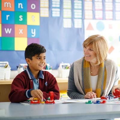 Female teacher seated with primary students at desk